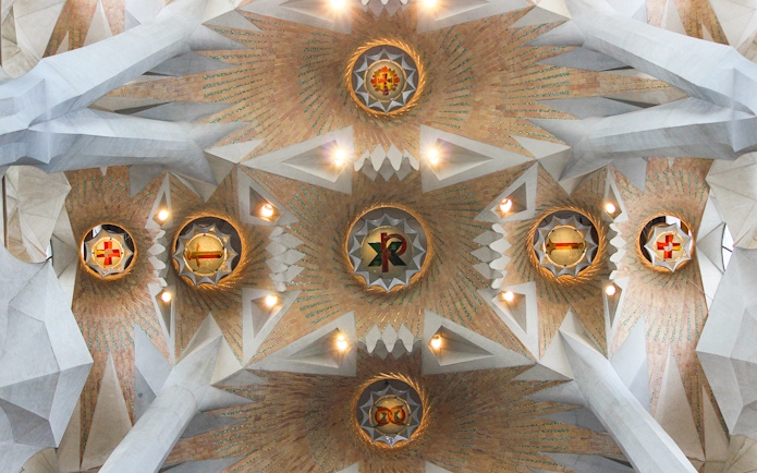 Ceiling detail of Sagrada Familia with geometric patterns and symbols, Barcelona.