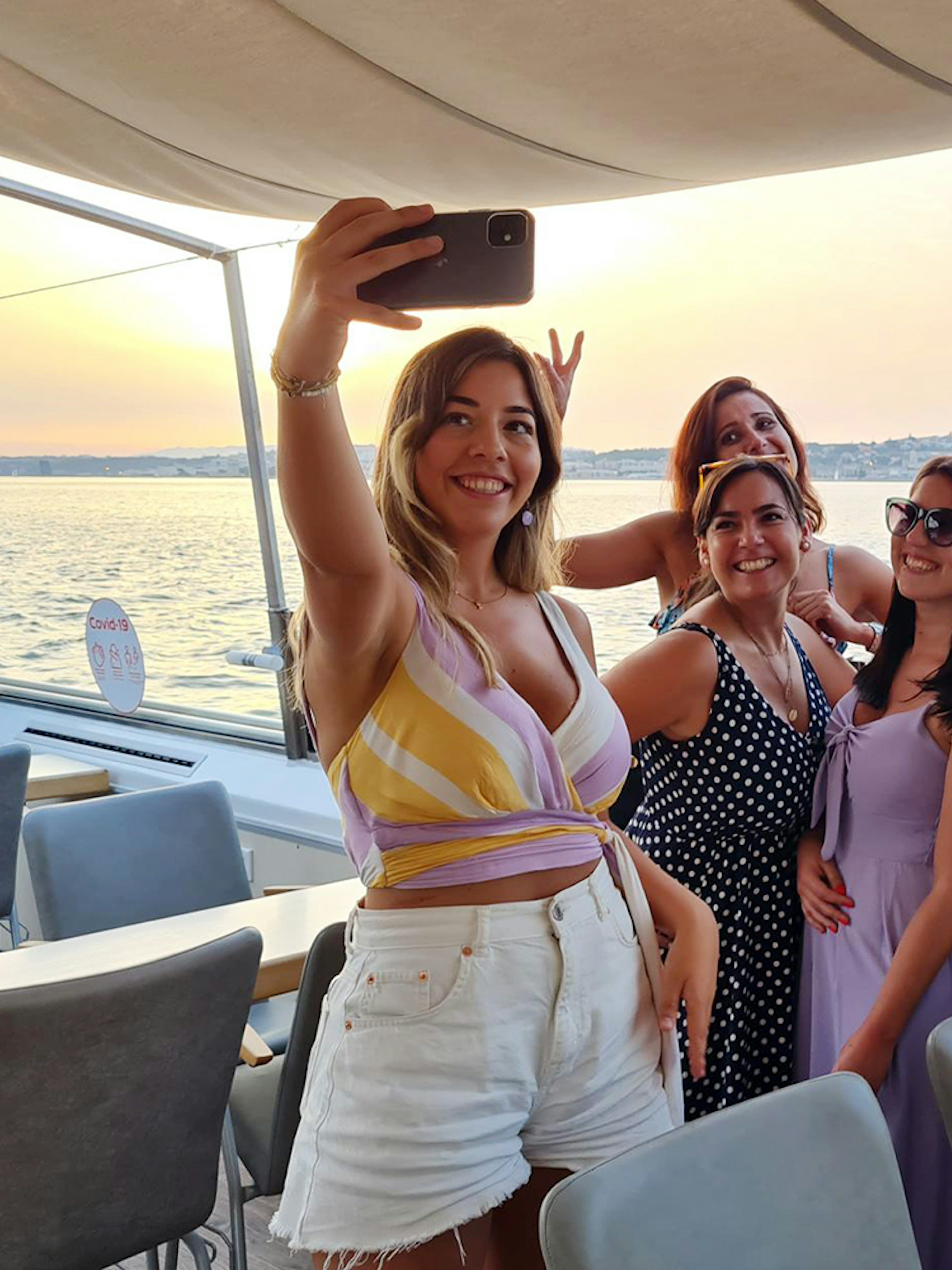 Group taking a selfie on a Tagus River boat cruise at sunset.