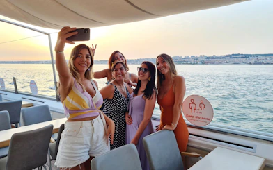 Group taking a selfie on a Tagus River boat cruise at sunset.