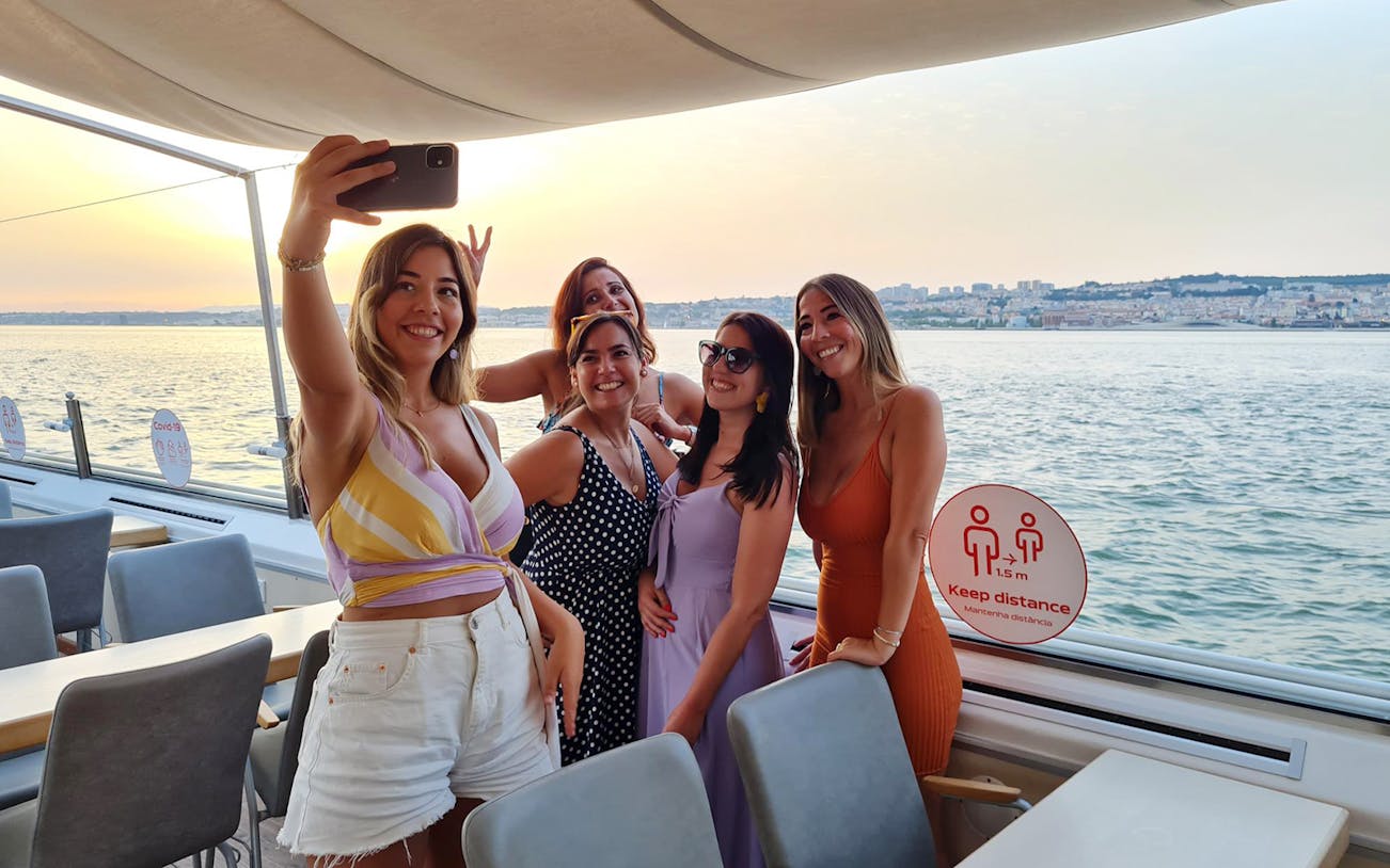 Group taking a selfie on a Tagus River boat cruise at sunset.