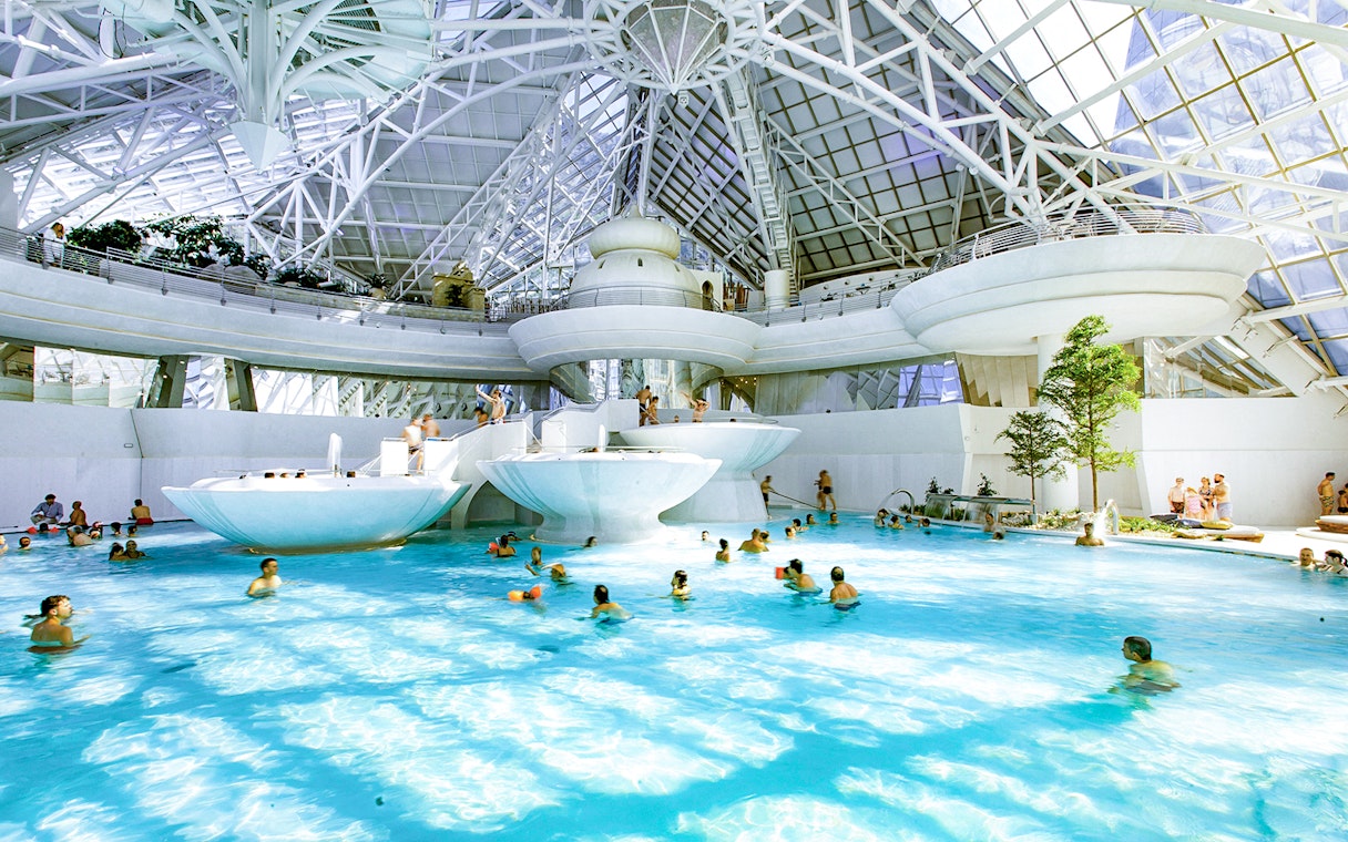 Indoor thermal pool at Caldea spa complex, Andorra, with visitors enjoying the water.