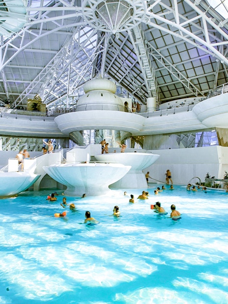 Indoor thermal pool at Caldea spa complex, Andorra, with visitors enjoying the water.