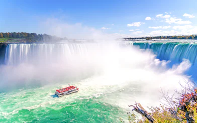 Tour boat approaching Niagara Falls with mist rising, Ontario, Canada.