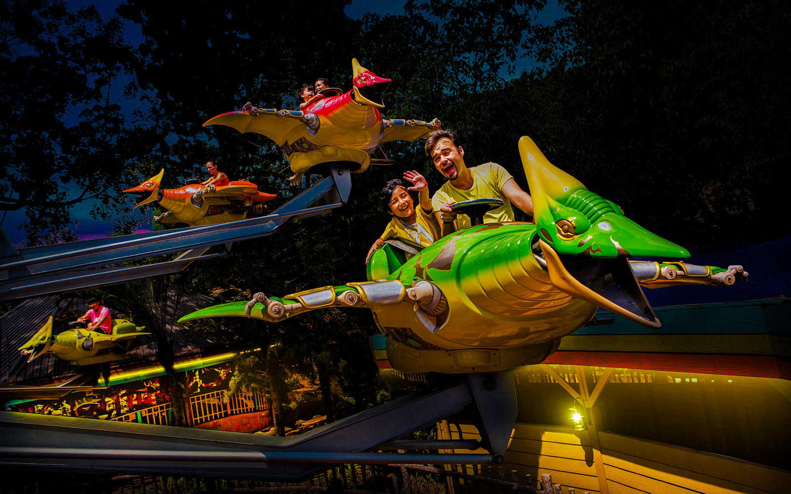 Riders enjoying a flying dinosaur ride at Sunway Lagoon night park.