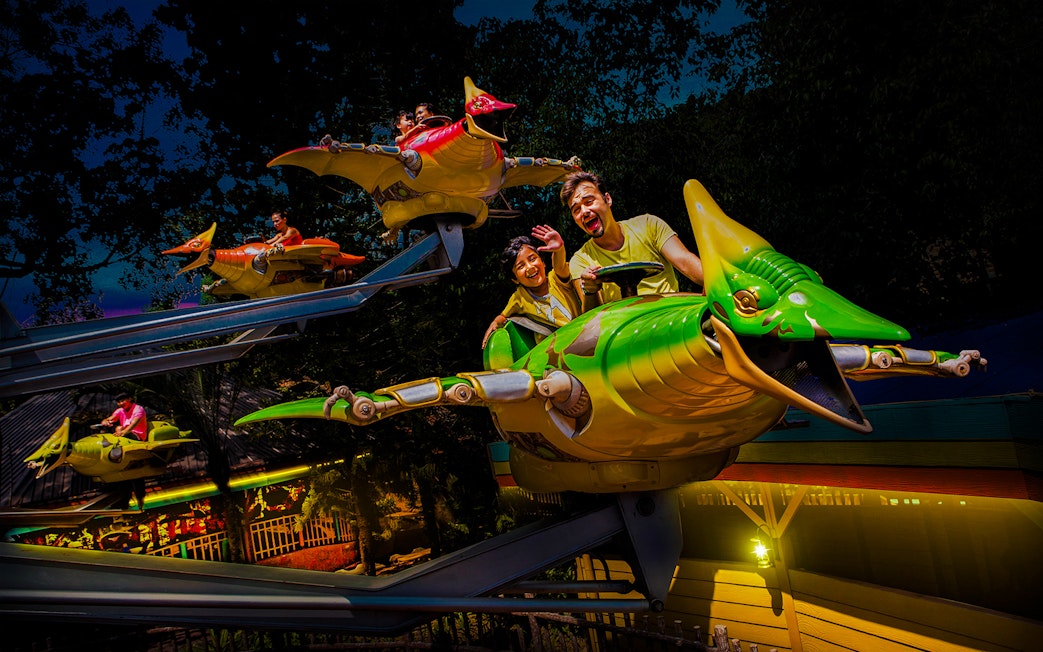 Riders enjoying a flying dinosaur ride at Sunway Lagoon night park.