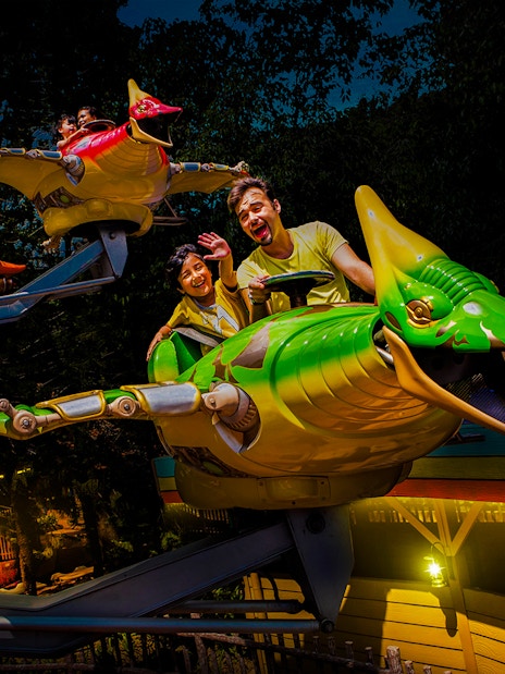 Riders enjoying a flying dinosaur ride at Sunway Lagoon night park.