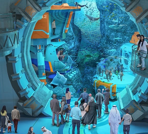 Visitors exploring an underwater-themed attraction with large aquarium and marine life.