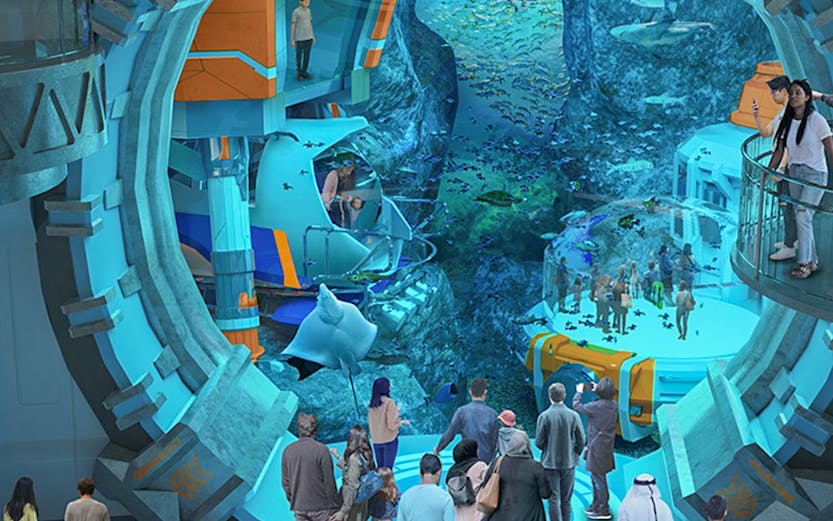 Visitors exploring an underwater-themed attraction with large aquarium and marine life.