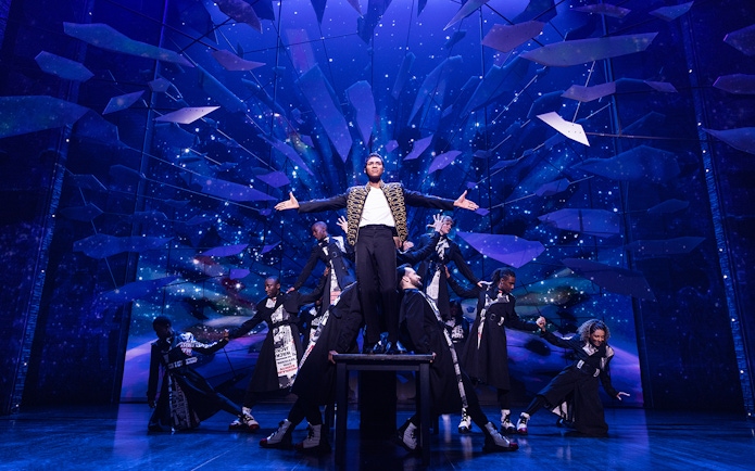 Performer on stage with dancers at MJ Live Tribute Concert.