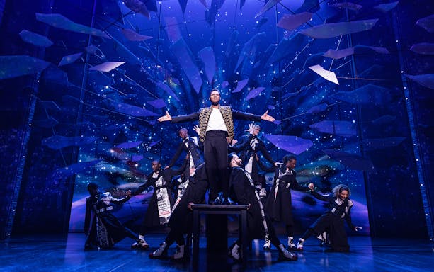 Performer on stage with dancers at MJ Live Tribute Concert.