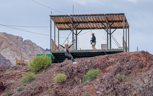 Person ziplining at Hatta Wadi Hub with rocky landscape in the background.