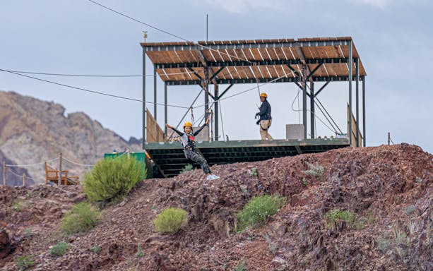 Person ziplining at Hatta Wadi Hub with rocky landscape in the background.