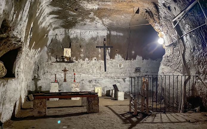 Underground chapel in Naples with stone altar, crosses, and religious icons.