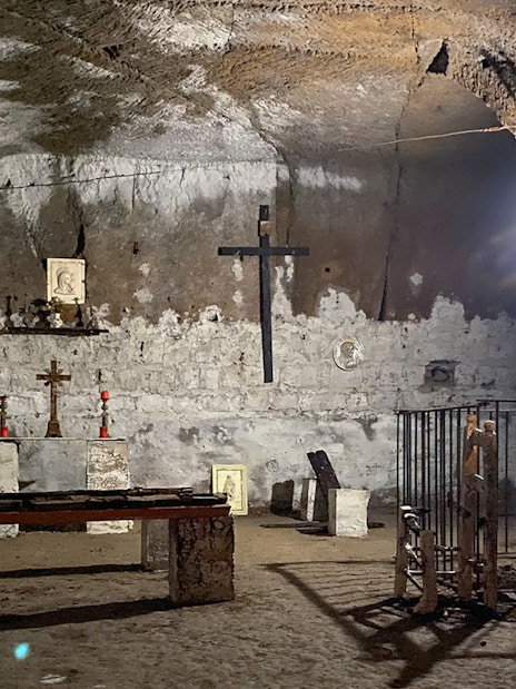 Underground chapel in Naples with stone altar, crosses, and religious icons.