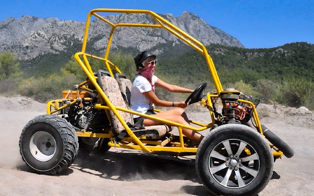 Buggy driving on a dirt trail with mountains in the background during Alanya Buggy Safari tour.