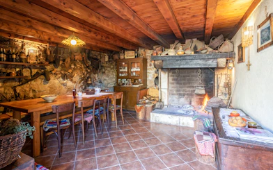 Dining area with wooden table and chairs, stone fireplace, and rustic decor in a Konavle, Croatia country house.