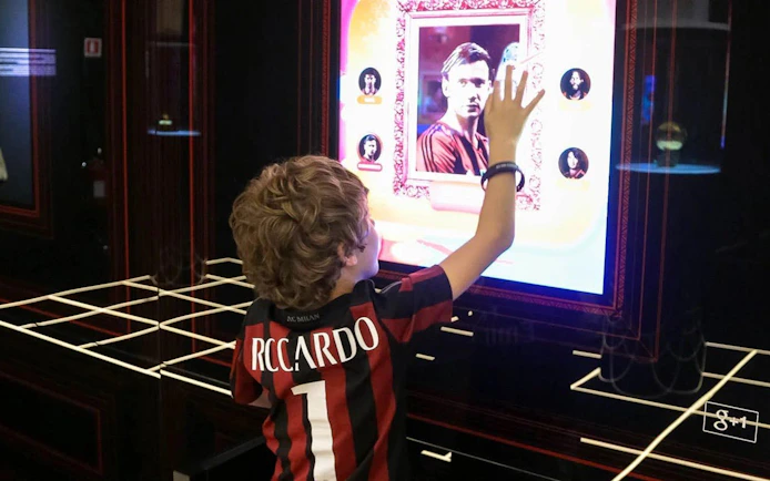 Child interacting with digital display at Casa Milan Museum, Italy.