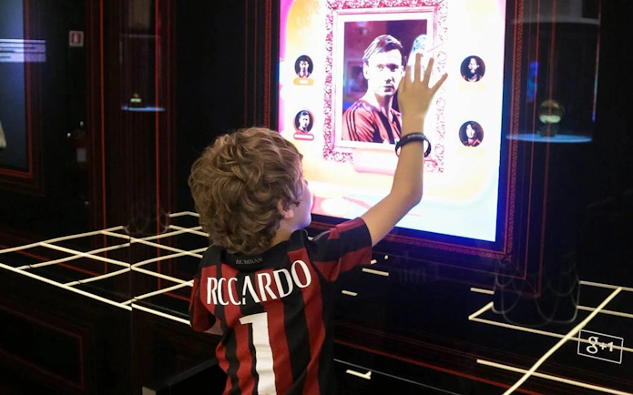 Child interacting with digital display at Casa Milan Museum, Italy.