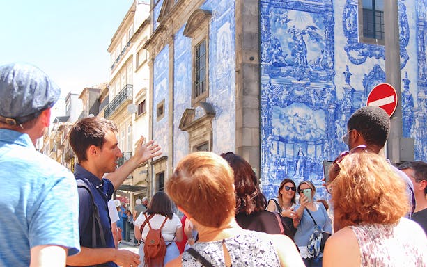 Tour group exploring azulejo tiles on a historic building in Porto.