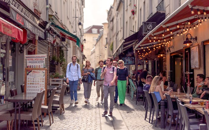 Tourists walking through a lively street in the Latin Quarter during a guided tour.