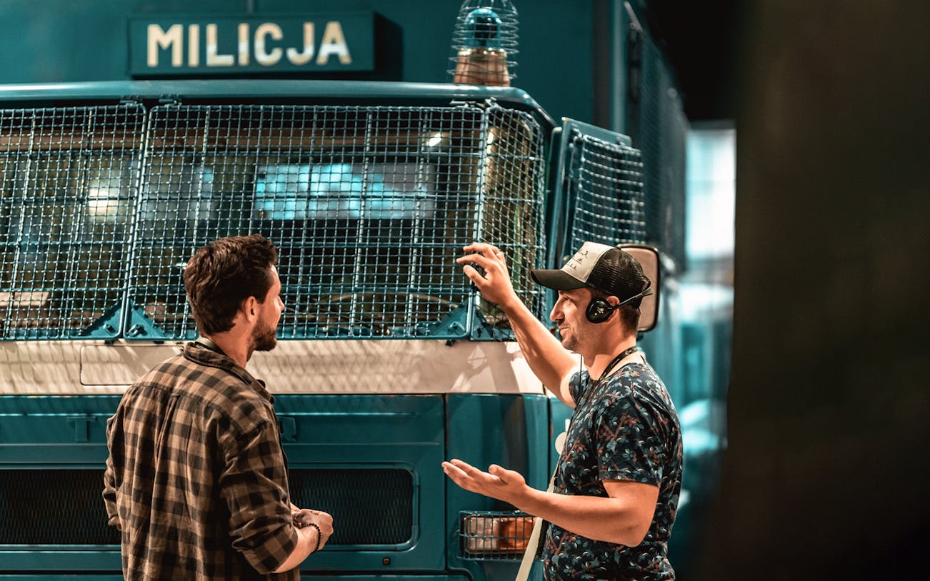 Guide explaining a historical police vehicle to a tourist at the European Solidarity Center.