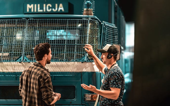 Guide explaining a historical police vehicle to a tourist at the European Solidarity Center.