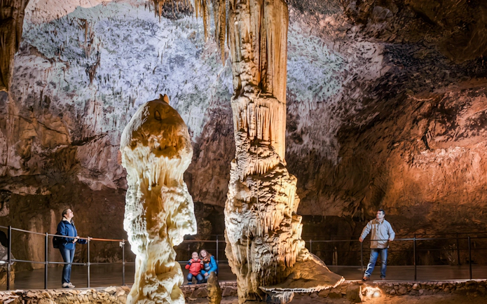 Visitors exploring stalagmites in Postojna Cave, Slovenia.