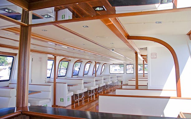 Interior of a deluxe boat for La Maddalena Archipelago tour with seating and windows.