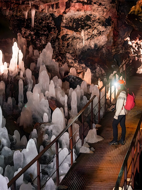 Guest exploring volcanic crystals in Raufarhólshellir Lava Cave, Iceland.
