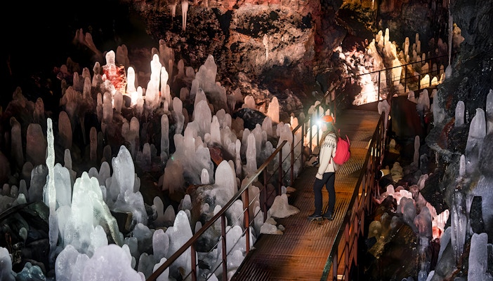 Guest exploring volcanic crystals in Raufarhólshellir Lava Cave, Iceland.