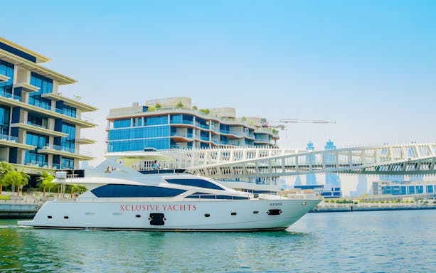 Yacht cruising through Dubai canal with skyline and Burj Khalifa in the background.