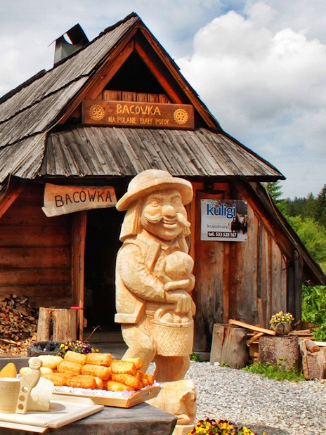 Wooden hut in Zakopane with traditional cheese display and carved figure.