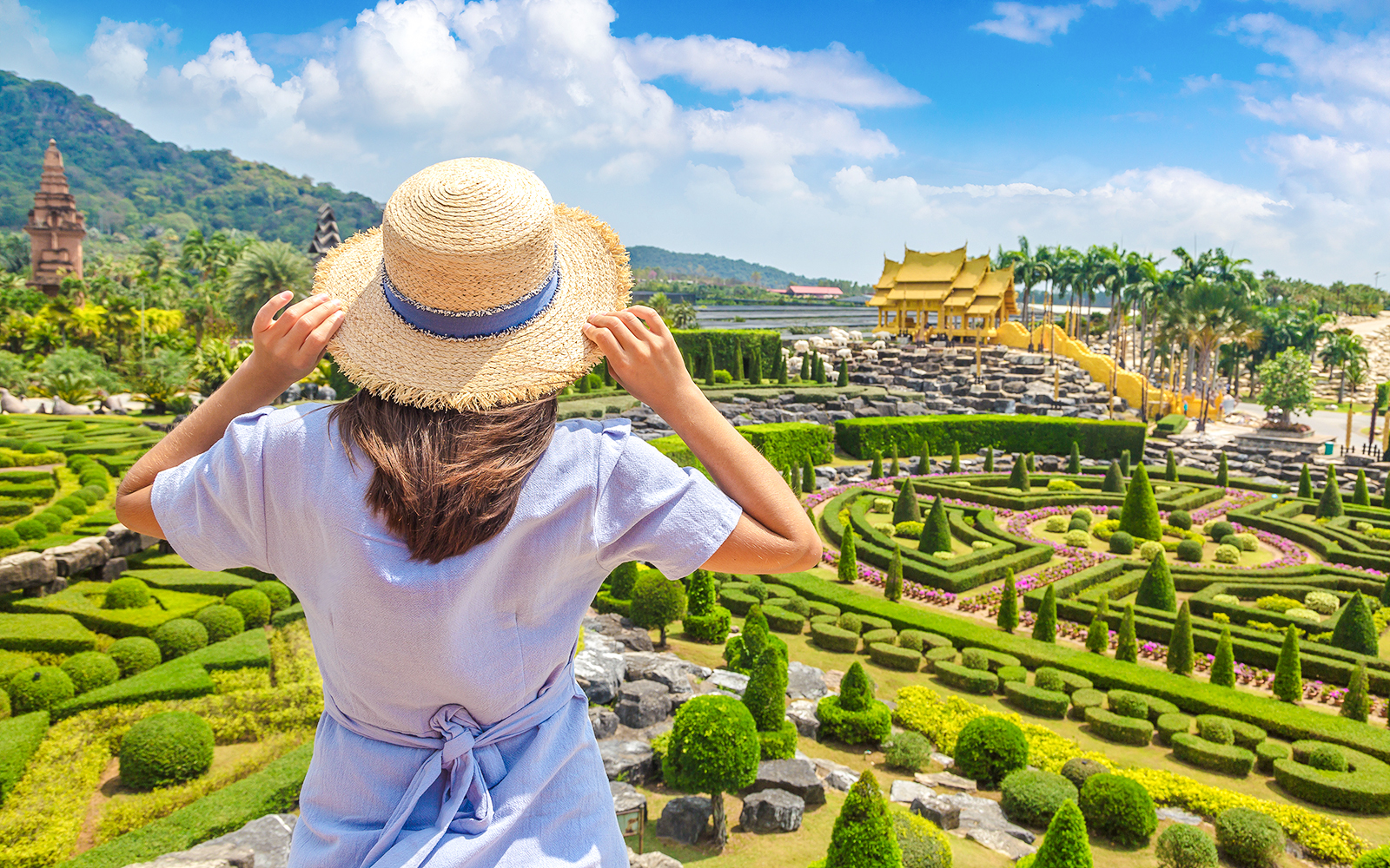 Woman exploring Nong Nooch Tropical Garden in Pattaya, Thailand, surrounded by vibrant floral displays and lush greenery.