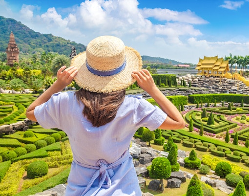 Woman exploring Nong Nooch Tropical Garden in Pattaya, Thailand, surrounded by vibrant floral displays and lush greenery.