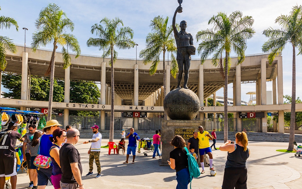 Crowd at Maracanã Stadium entrance, Rio de Janeiro, with a statue of a football player.