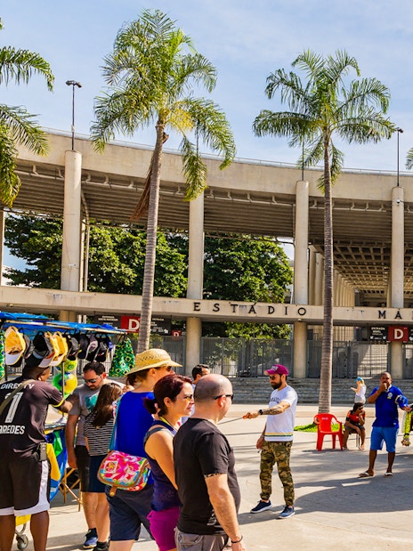 Crowd at Maracanã Stadium entrance, Rio de Janeiro, with a statue of a football player.