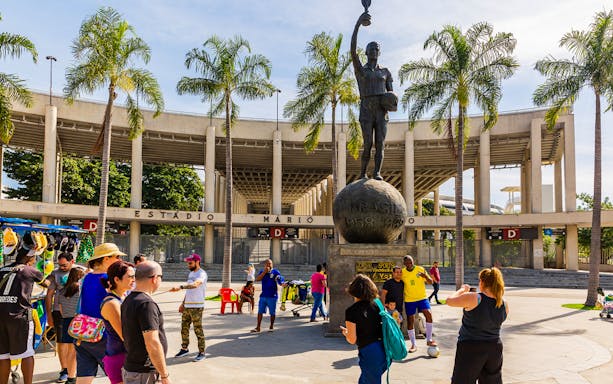 Crowd at Maracanã Stadium entrance, Rio de Janeiro, with a statue of a football player.