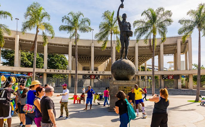 Crowd at Maracanã Stadium entrance, Rio de Janeiro, with a statue of a football player.