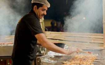Man grilling skewers during Abu Dhabi evening desert safari.