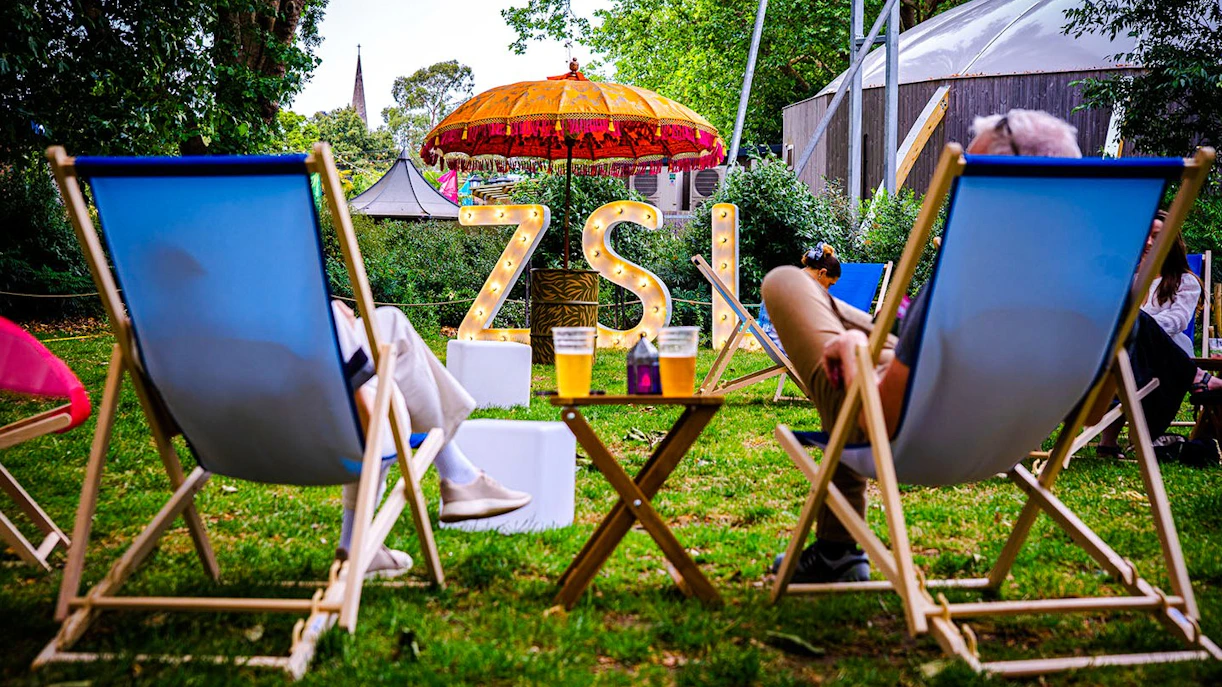 Guests relaxing in deck chairs at London Zoo after hours event.