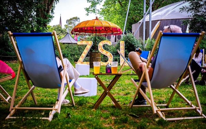 Guests relaxing in deck chairs at London Zoo after hours event.