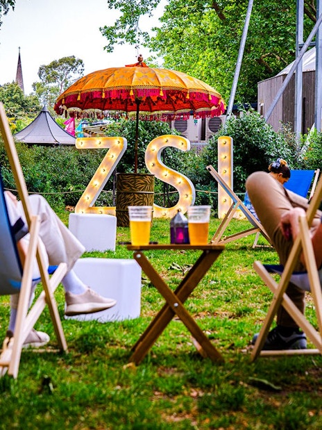 Guests relaxing in deck chairs at London Zoo after hours event.