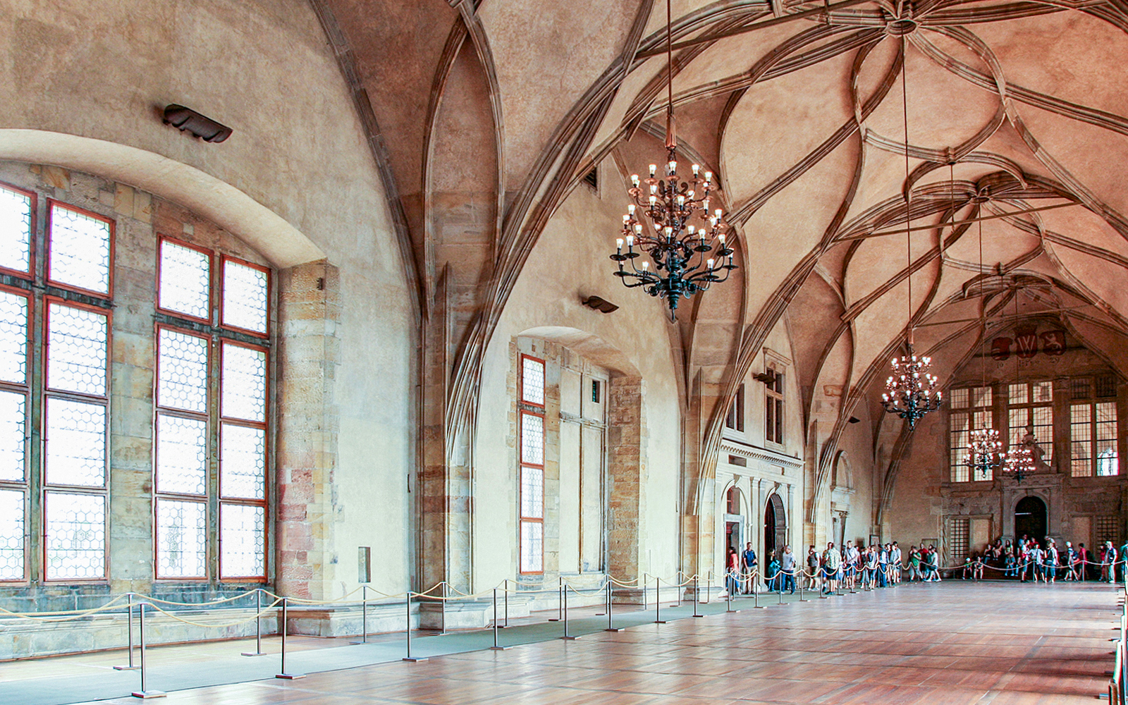 Prague Castle interior with vaulted ceilings and chandeliers during guided tour.