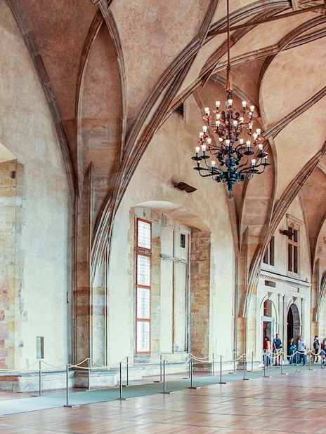 Prague Castle interior with vaulted ceilings and chandeliers during guided tour.