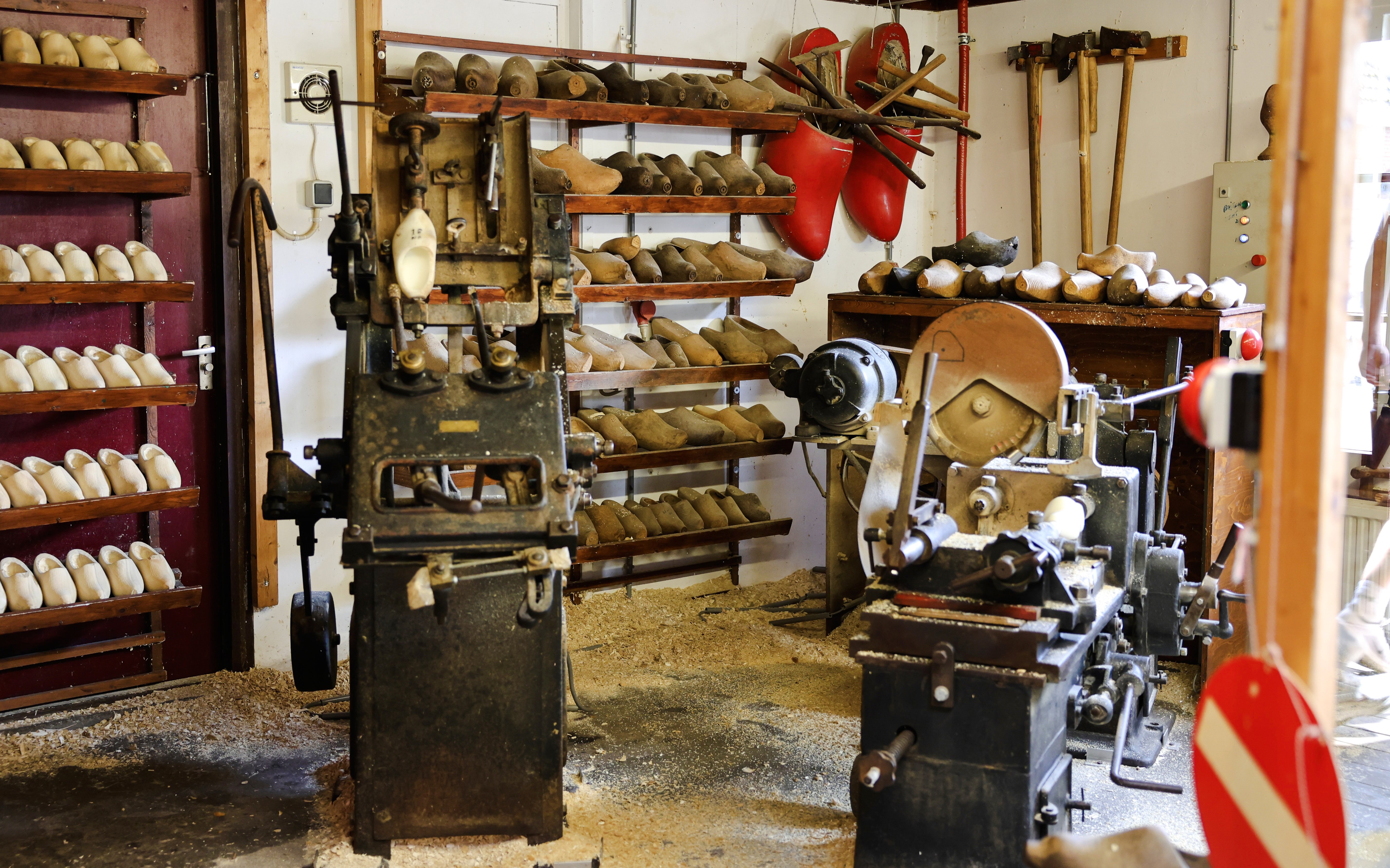 Clog-making workshop with wooden shoe molds and machinery, showcasing traditional Dutch craftsmanship.