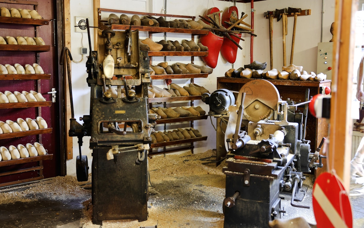 Clog-making workshop with wooden shoe molds and machinery, showcasing traditional Dutch craftsmanship.