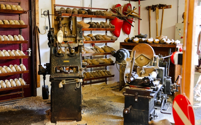 Clog-making workshop with wooden shoe molds and machinery, showcasing traditional Dutch craftsmanship.