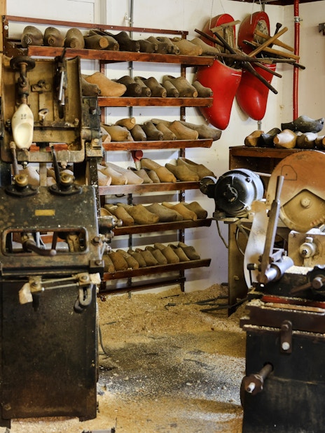 Clog-making workshop with wooden shoe molds and machinery, showcasing traditional Dutch craftsmanship.