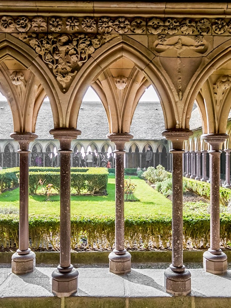 Cloister arches and garden at Mont St. Michel Abbey, France.