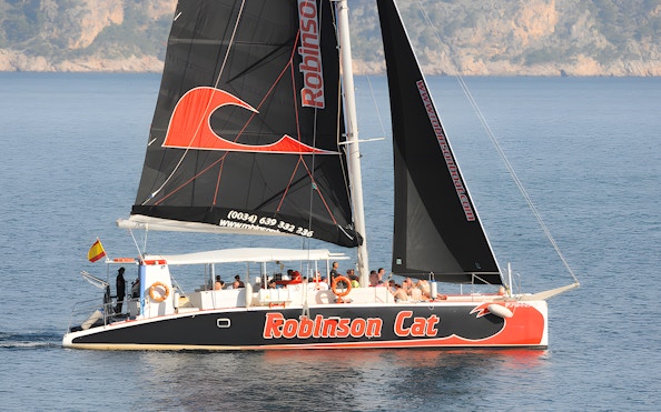 Catamaran sailing near Mallorca coast for sunrise and dolphin watching tour.